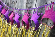 purple and pink crowns hanging on a wooden fence