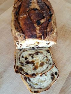 a loaf of bread sitting on top of a wooden cutting board with raisins