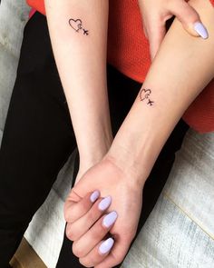 two people with matching tattoos on their arms, one holding the other's hand