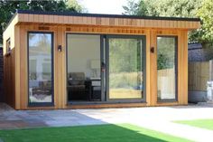 a small wooden building with sliding glass doors on the outside and grass in the yard