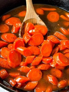 carrots are being cooked in a pot with a wooden spoon