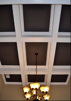 a chandelier hanging from the ceiling in a room with dark walls and white trim