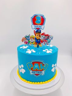 a blue cake with paw patrol characters on it