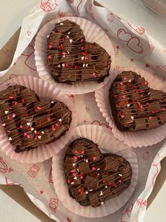 four chocolate heart shaped cookies sitting on top of paper plates