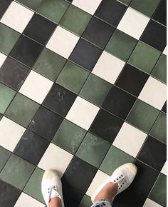 a person standing on a tiled floor with white and green shoes