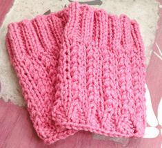 two pink knitted mittens sitting on top of a table