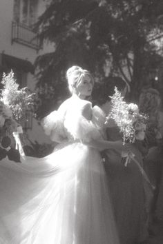 black and white photo of woman in wedding dress holding flowers with people watching from the side