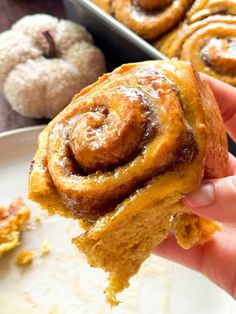 a person holding up a cinnamon roll in their hand