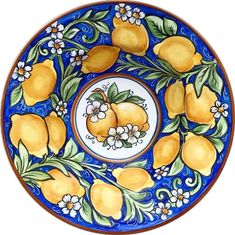 a blue and white plate with lemons painted on the side, surrounded by flowers