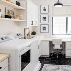 a washer and dryer sitting in a kitchen next to a window with pictures on the wall