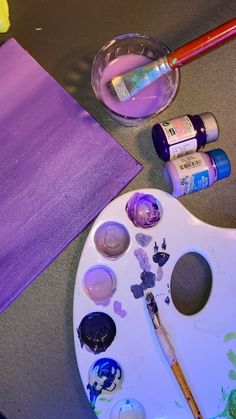 an artist's palette with paint, brushes and other art supplies on a table