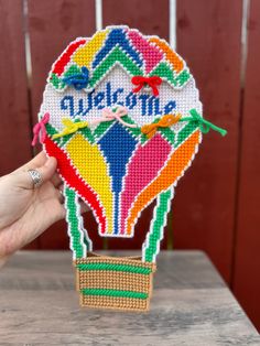 a hand holding up a cross stitch hot air balloon with the words wake me on it