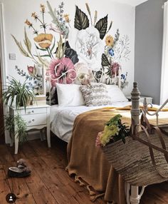 a bedroom decorated with flowers and plants on the wall, along with a wicker basket