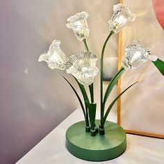 a green vase with flowers in it sitting on a table