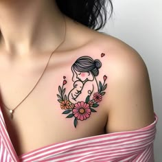 a woman with a tattoo on her shoulder holding a baby in the middle of flowers