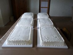 two cakes sitting on top of a table covered in white frosting and decorated with monograms