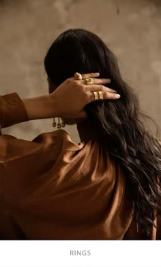 a woman with long hair wearing gold rings