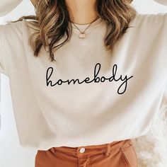 a woman wearing a white sweatshirt with the word homeboy printed on it, in front of her face