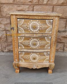 an ornate wooden chest of drawers in front of a brick wall