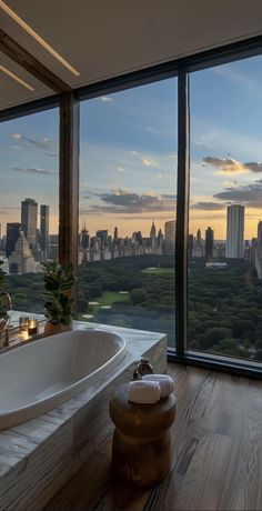 a bath tub sitting next to a large window with a view of the city skyline