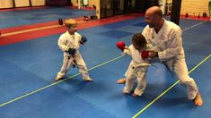 two children and an adult are practicing karate in a gym with one man holding a red ball