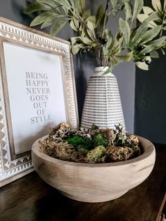 a wooden bowl with plants in it next to a photo frame