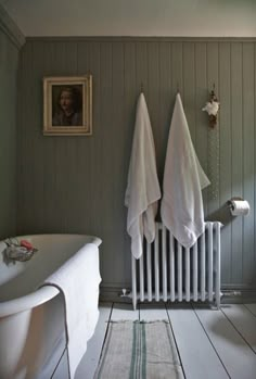 two white towels hanging on the wall next to a radiator in a bathroom