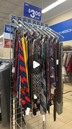 a rack filled with lots of ties in a clothing store next to a sign that says $ 300