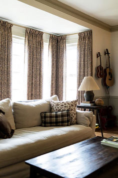 a living room filled with furniture and a guitar on the wall behind the couches