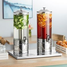 two juice dispensers sitting on top of a counter next to each other