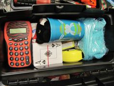 an open suitcase filled with assorted items including a calculator, pencils and pens