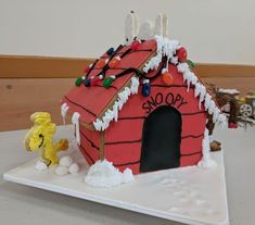 there is a cake that looks like a doghouse with lights on it and snow all over the roof