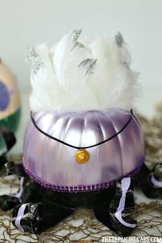 there is a small white dog in a purple hat on top of a table next to other figurines