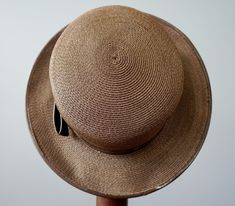 "DESCRIPTION * Vintage hat from 1950s-1960s * boater hat style: flat crown, straight brim * made of brown woven straw * the hatband is wrapped with grosgrain ribbon and trimmed with faux patent leather * embellished with a bow on the side * Union Made tag hat is really large. When shipped, the brim might be slightly bent but not folded in order to keep the shipping cost low. CONDITION the hat is in good vintage condition and shows signs of normal use. There are two spots of stains near the metal Retro Adjustable Brimmed Boater Hat, Adjustable Brimmed Retro Boater Hat, Vintage Adjustable Boater Hat With Curved Brim, Vintage Flat Brim Panama Hat For Kentucky Derby, Vintage Panama Hat For Kentucky Derby With Flat Brim, Vintage Fitted Brown Panama Hat, Fitted Vintage Brown Panama Hat, Vintage Brimmed Panama Hat For Formal Occasions, Vintage Flat Brim Sun Hat For Kentucky Derby