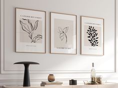 three black and white art prints hanging on the wall above a buffet with wine bottles