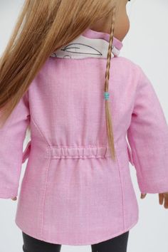 the doll is wearing a pink coat and black pants with braids on her hair