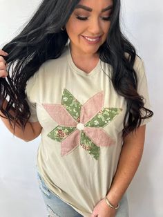 a woman with long black hair wearing a t - shirt that has a flower on it