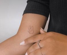 two hands holding each other with small tattoos on their wrist and fingers, one has a leaf tattoo on it