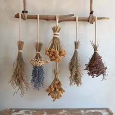 several dried flowers hanging from ropes on a wall next to a wooden table and bench