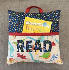 a pillow with the words read on it and an image of dinosaurs in blue, green, red