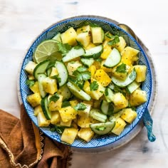 a blue and white bowl filled with cucumber, lemon and mint salad on top of a wooden table