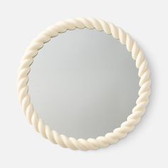 a round mirror made out of rope on a white surface with the reflection in it