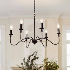 a chandelier hanging over a dining room table with flowers on it and candles in the center