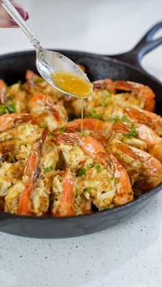 a pan filled with cooked shrimp being drizzled over it's sides