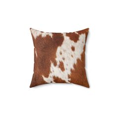 a brown and white cowhide pillow on a white background