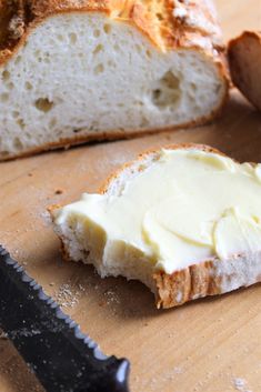 a piece of bread sitting on top of a wooden cutting board next to a knife