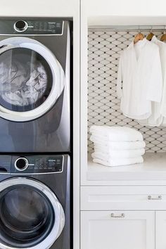 a washer and dryer in a white laundry room with clothes hanging on the rack