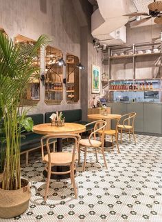 the interior of a restaurant with tables, chairs and potted plants on the floor