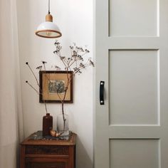 a vase with flowers is sitting on a table in front of a white door and light fixture