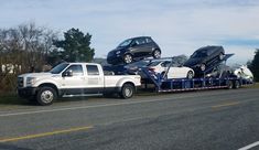 two cars are being loaded onto the back of a truck on the side of the road